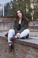 Portrait of a stylish, happy and beautiful hippie girl who sits in the park in cloudy weather