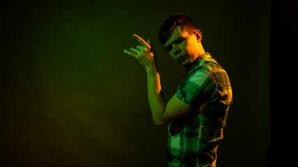 The guy in the checkered shirt dances, illuminated by orange and green light