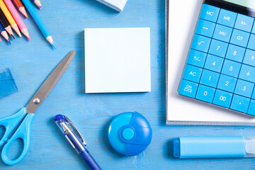 Calculator, pencils, note, eraser scissors, marker, sticky notes on the blue background.