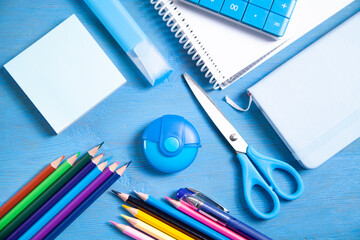 Calculator, pencils, note, eraser scissors, marker, sticky notes on the blue background.