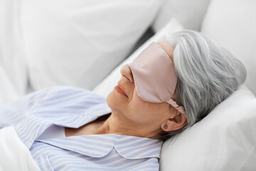 old age and people concept - senior woman with eye mask sleeping in bed at home bedroom