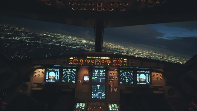Airplane flying over city at night. Able to see beautiful view and city lights. View from inside cockpit. Pilot eye view.