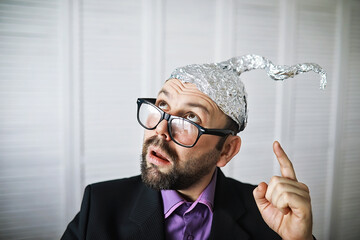 Bearded funny man in a cap of aluminum foil. Concept art phobias.Conspiracy theory. Conspiracy....