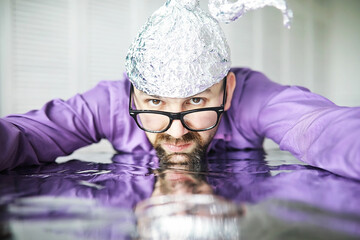 Bearded funny man in a cap of aluminum foil. Concept art phobias.Conspiracy theory. Conspiracy....