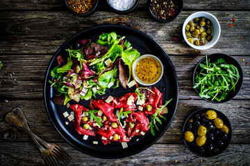 Beef carpaccio  with parmesan, capers, and arugula on wooden table
