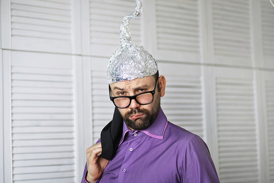 Bearded funny man in a cap of aluminum foil. Concept art phobias.Conspiracy theory. Conspiracy. Insanity.