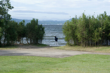 波打ちぎわで腕を組んで空を見上げる男性