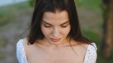 Portrait young woman at sunlight with long hair open eyes look at camera smiling fashion model female girl cosmetic beauty confident happy cheerful close up slow motion.