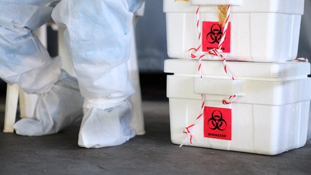The biohazard box stores a swab test covid-19 and a doctor wearing a PPE protective suit.