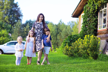 Obraz premium Young large family on a summer morning walk. Beautiful mother with children is playing in the park.