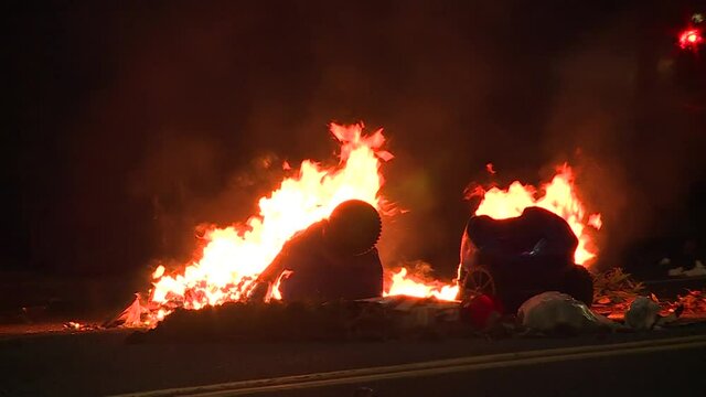 PLASTIC TRASH CANS BURNING DURING RIOT AT NIGHT