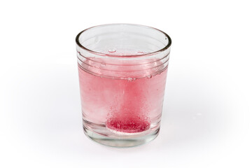 Effervescent tablet thrown into glass of water on light surface
