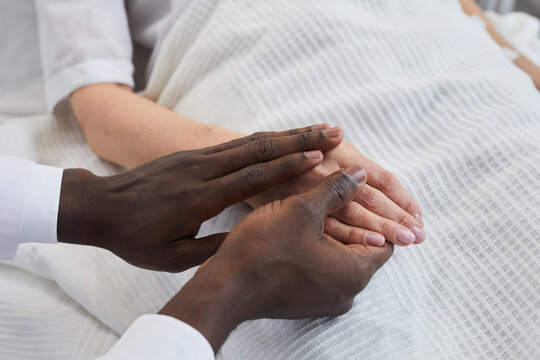 Close-up of African doctor holding hand of his patient at hospital