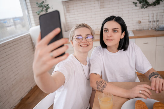 happy lesbian couple taking selfie in kitchen