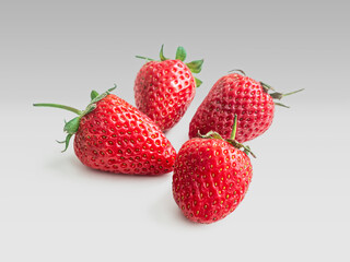 Ripe red strawberries with green leaves on a light background