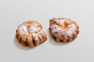 Two custard bagels with a golden crust, with powdered sugar