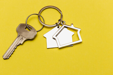 The concept of mortgage and rental housing and real estate. Mortgage credit lending. Keychain in the shape of a house with a key on a yellow background.