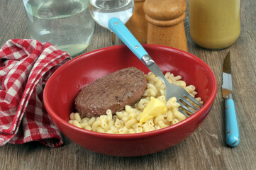 Steak haché de boeuf et pâtes au beurre servis dans une assiette avec une fourchette