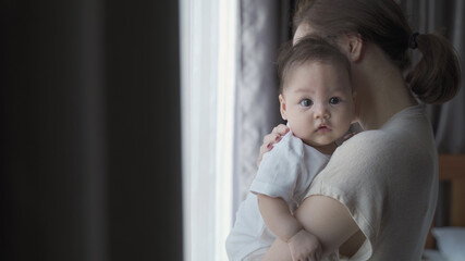 portrait of happy asian woman mother holding sleepy baby infant near window at home daytime. 4...