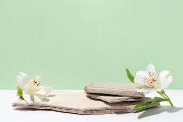 Obraz na płótnie Canvas Background for cosmetic products of natural green color. Stone podium with white flowers. Front view.