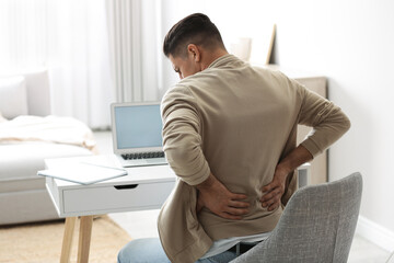 Man suffering from back pain at workplace. Bad posture problem