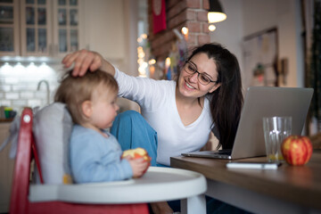 Obraz premium Mother with small daughter in kitchen, home office with children concept.