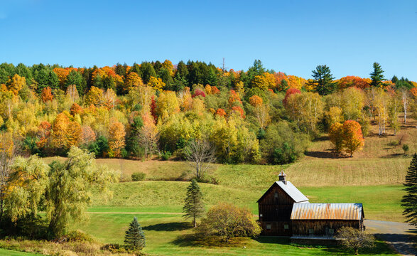A quiet farm house sitting in solitary in front of a vibrant foliage. Vermont, United States
