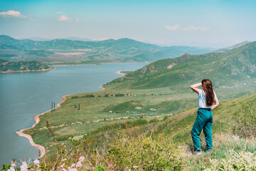 Fototapeta na wymiar Young woman standing against blue sea and mountains background East Kazakhstan