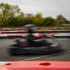 A panning shot of a racing kart as it circuits a track.