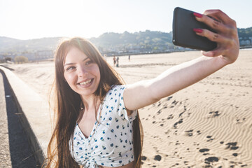 Young woman taking a selfie with a mobile phone at the beach side