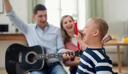 Cheerful down syndrome boy with parents playing musical instruments, laughing.