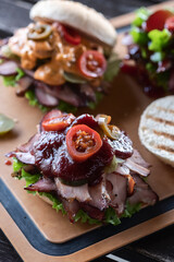 Burgers with smoked turkey slices, green lettuce, jalapeno pepper and sauce.