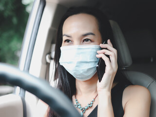 Fototapeta na wymiar beautiful Asian woman wearing medical face mask, talking on mobile phone in the car. Covid-19 protection ,new normal and safety concept.