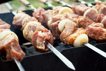 Marinated shashlik preparing on a barbecue grill over charcoal. Shashlik or Shish kebab popular in...