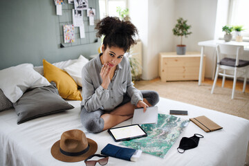Young woman with tablet and map indoors at home, planning traveling trip.