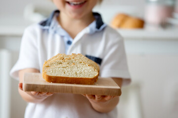 Child, blond toddler boy, holding wooden cutting board with homemade ciabatta bread, serving at home