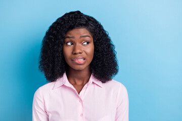 Photo of pretty doubtful dark skin woman wear pink outfit biting lip looking empty space isolated...