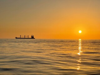 Fototapeta na wymiar Silhouette of a freight ship on the horizon of the Mediterranean sea during sunset