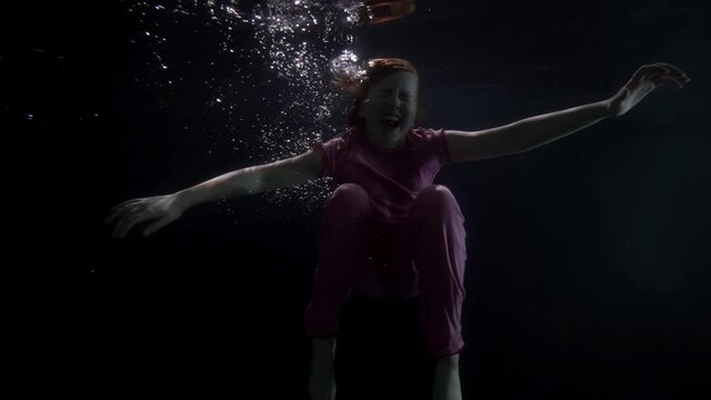 slow motion baby girl in pajamas underwater in zero gravity screams like a nightmare dream