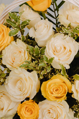 Flower arrangement in basket with white, yellow and pistachio roses.