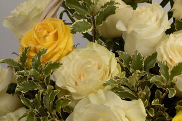 Flower arrangement in basket with white, yellow and pistachio roses.