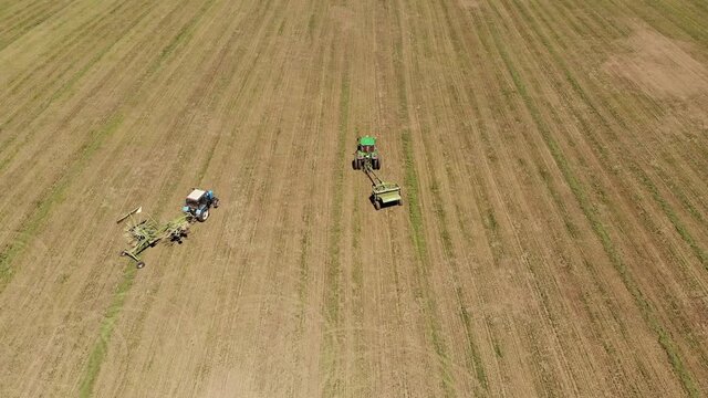 Aerial view of a tractor with a mower mows the grass on an empty field. Field preparation and maintenance throughout the year