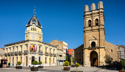 Fototapeta na wymiar Cityscape of old town La Bañeza in Castile and Leon, Spain, with historic town hall building and landmark Saint Mary church on the main town square.