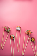 sushi rolls with chopsticks on pink background