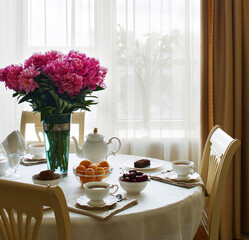 table setting a table in the living room set for tea with flowers in front of the window