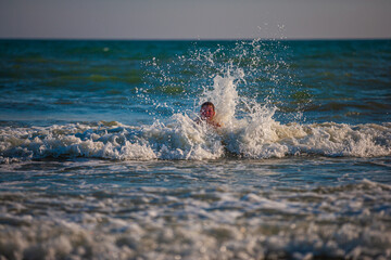 Boy on the beach, playing with the waves, summer time