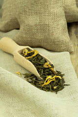 Dried green tea leaves in a wooden spoon