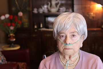 Senior woman using nasal breathing aid at home
