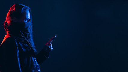 Female activist. Social banner. Threat warning. Profile portrait of woman in face bandana mask pointing finger at empty space in dark red blue neon light isolated on night background.