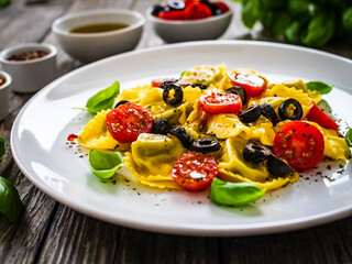 Tortelloni stuffed with prosciutto ham and vegetables on wooden table